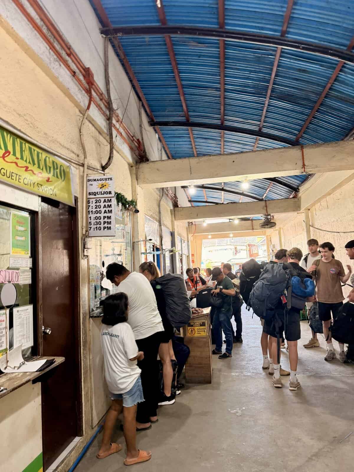 Dumaguete Port showing locals and tourists, and picture of a timetable of one of the companies selling boat tickets towards Siquijor island
