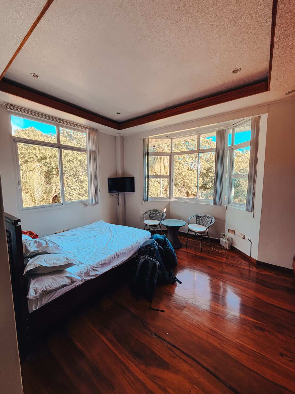 Spacious room at Camiguin Lanzones Resort with wooden floors, large windows, and views of lush trees outside creating a cozy tropical atmosphere. The bright interior and natural surroundings highlight this comfortable Camiguin accommodation option for travelers seeking a peaceful stay.