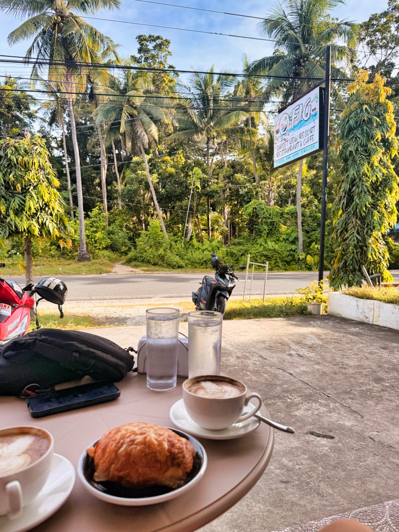 Morning coffee and breakfast served on a small cafe table with natural light, surrounded by palm trees. Relaxed cafes like this are part of the daily island life around San Juan.