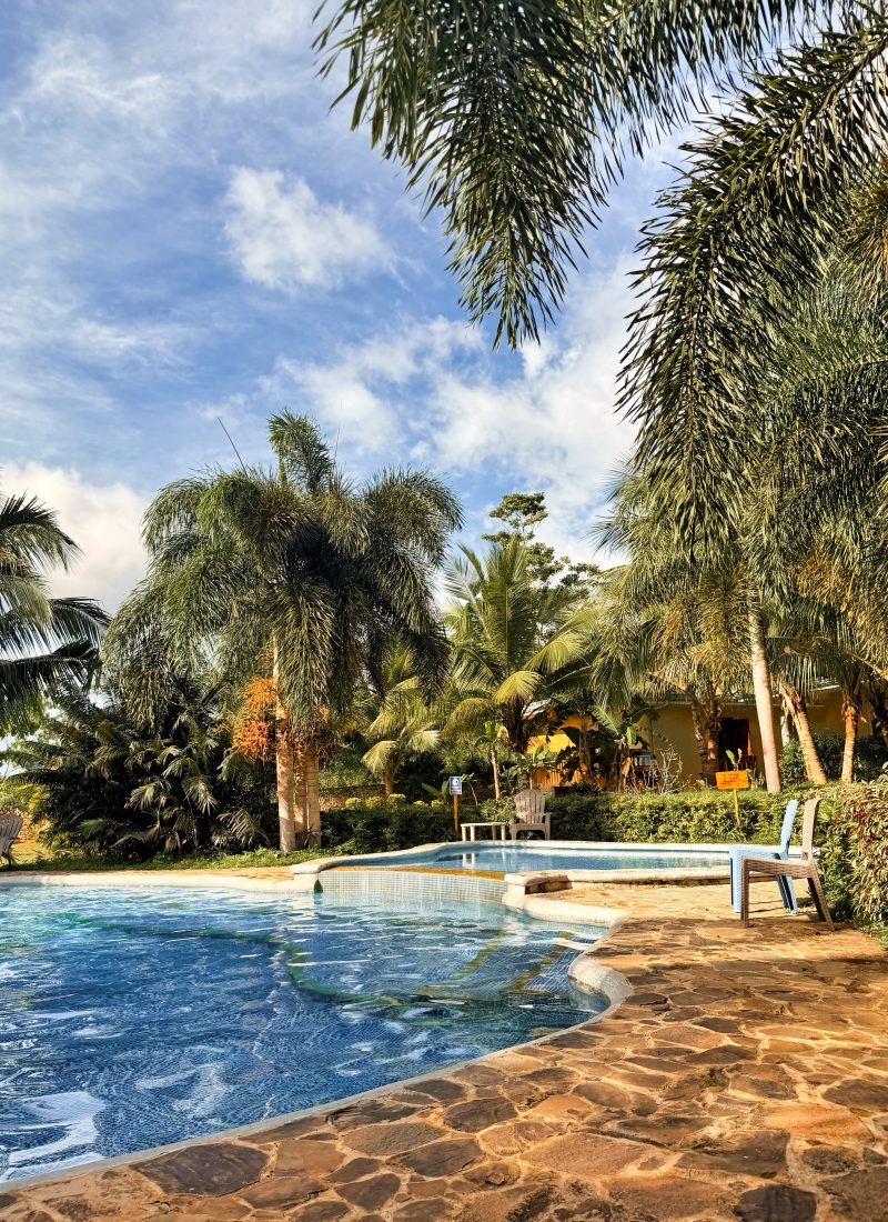 Pool of a resort in Siquijor in golden lights, surrounded by palm trees.