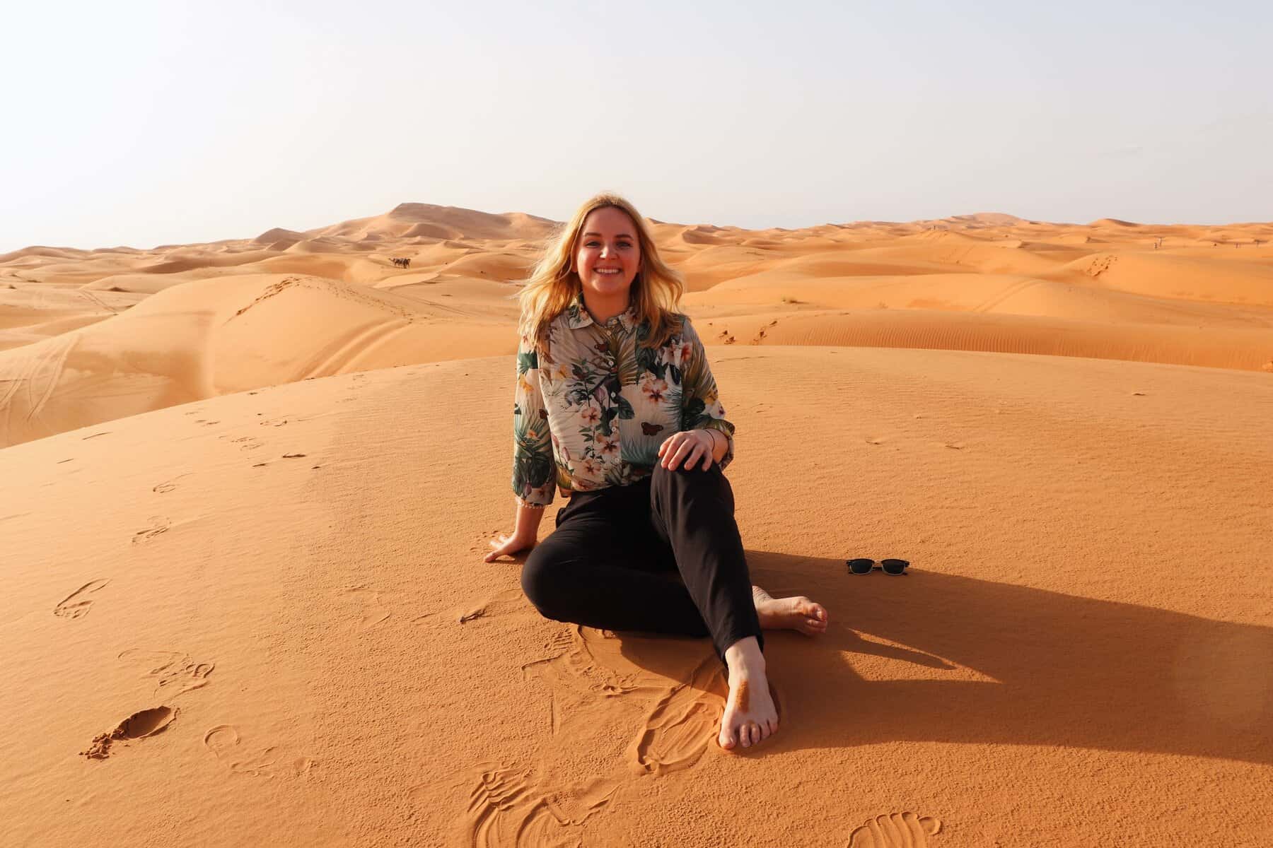 Author smiling in desert sand dunes landscape during solo travel adventures before starting travel blog – Years of destination experience