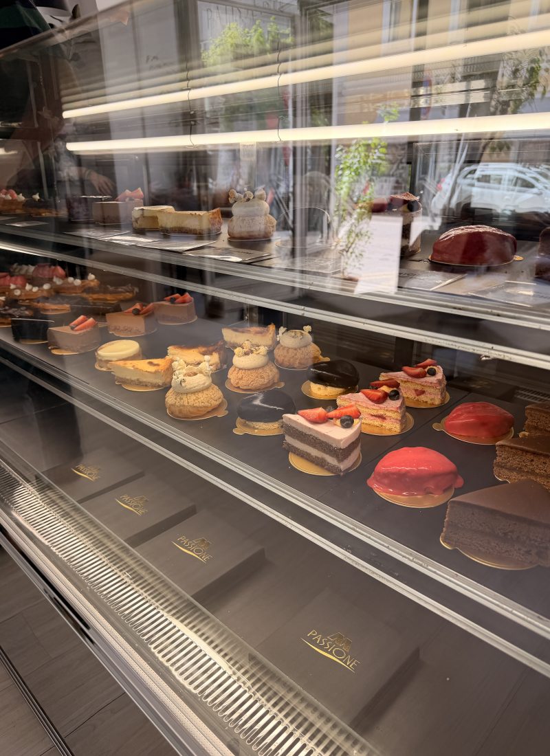 Elegant cakes, cheesecakes, and colorful pastries displayed inside Passione Patisserie in Salzburg city centre.