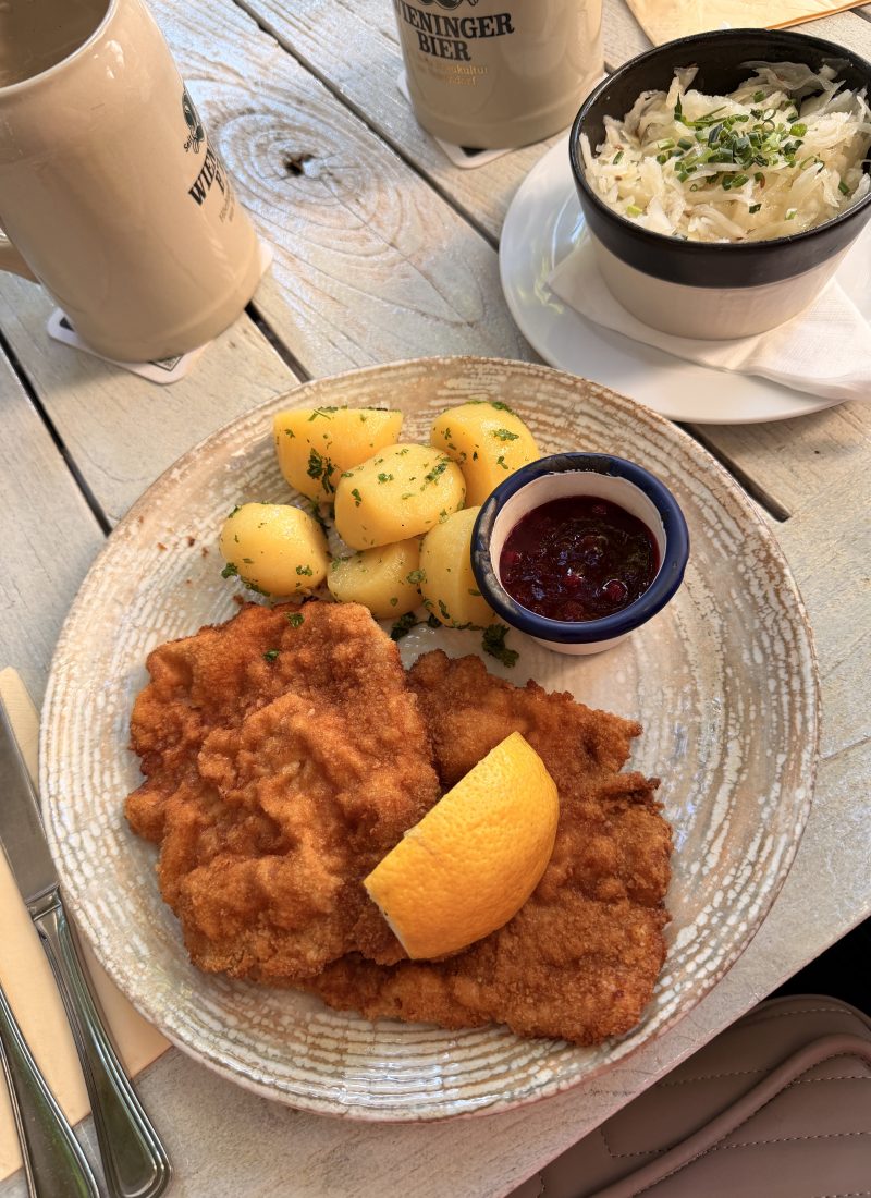 Traditional Wiener Schnitzel served with parsley potatoes, lingonberry sauce, and sauerkraut at a restaurant in Salzburg, Austria.