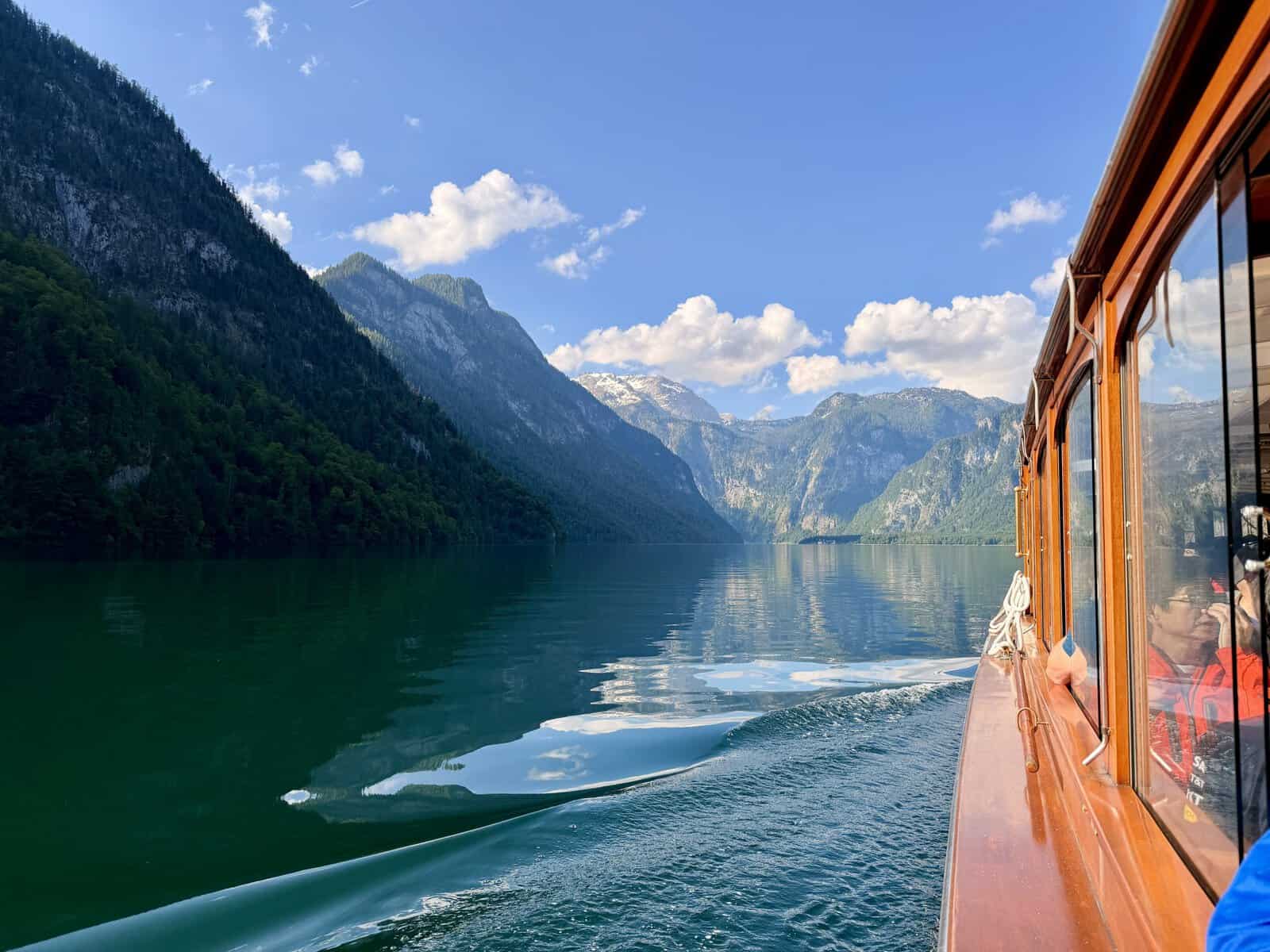View from a wooden passenger boat crossing Königssee toward Salet, surrounded by calm alpine water and the Berchtesgaden mountains.