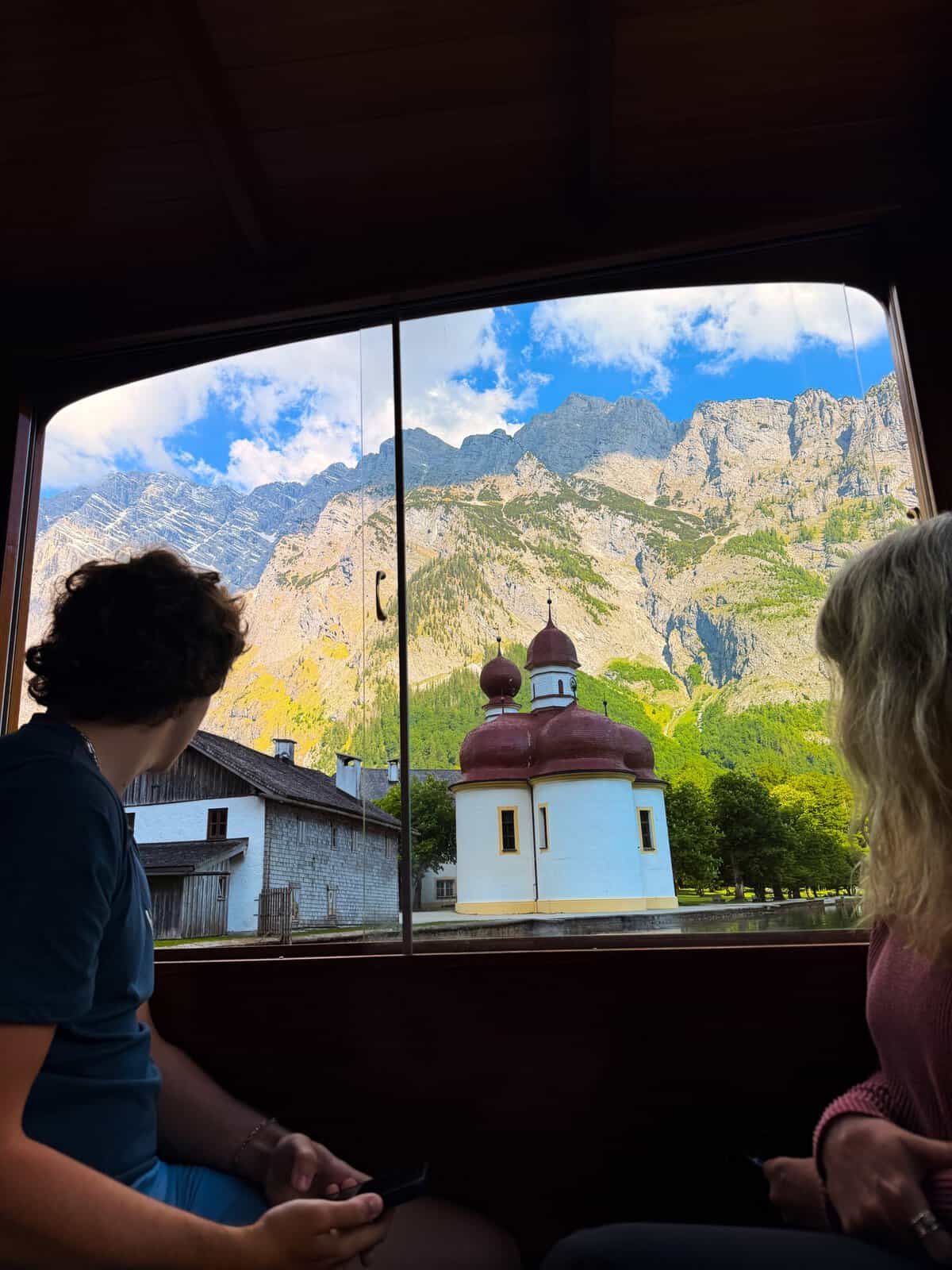 View of St. Bartholomä Church and alpine mountains from a boat on Lake Königssee in Bavaria, Germany.