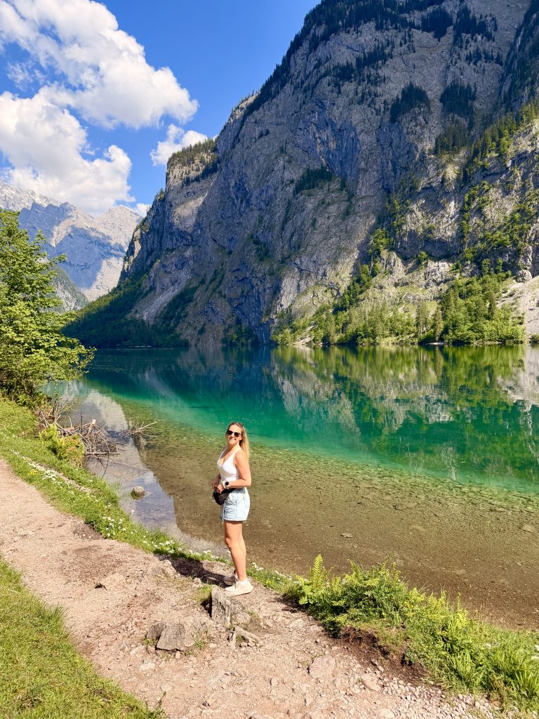 Traveler beside turquoise Obersee near Salet, surrounded by forest and steep alpine cliffs
