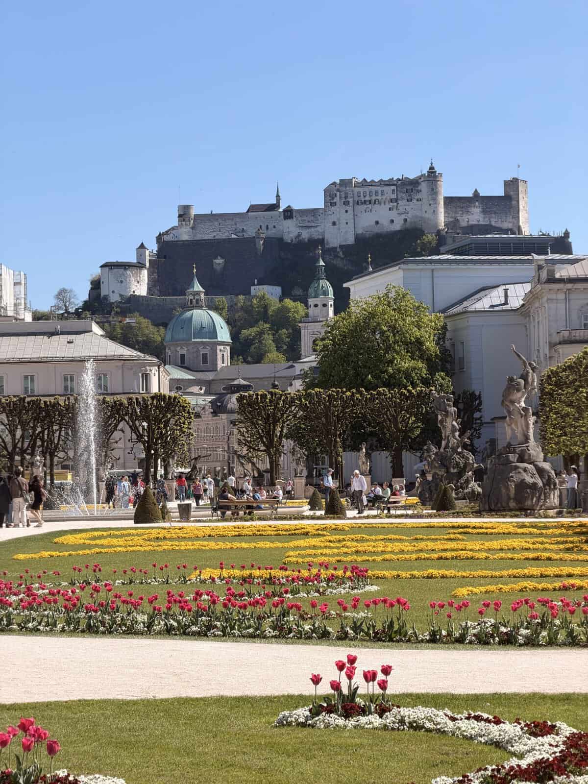 Mirabell Gardens in Salzburg, a filming location from The Sound of Music, featuring colorful flower beds, fountains, and views of Hohensalzburg Fortress.
