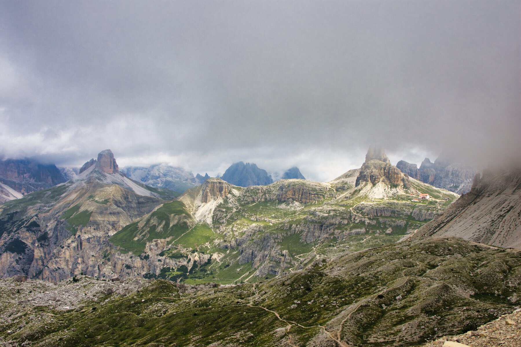 Cloud-covered mountain peaks, hiking trails and a remote refuge in the Dolomites, Italy