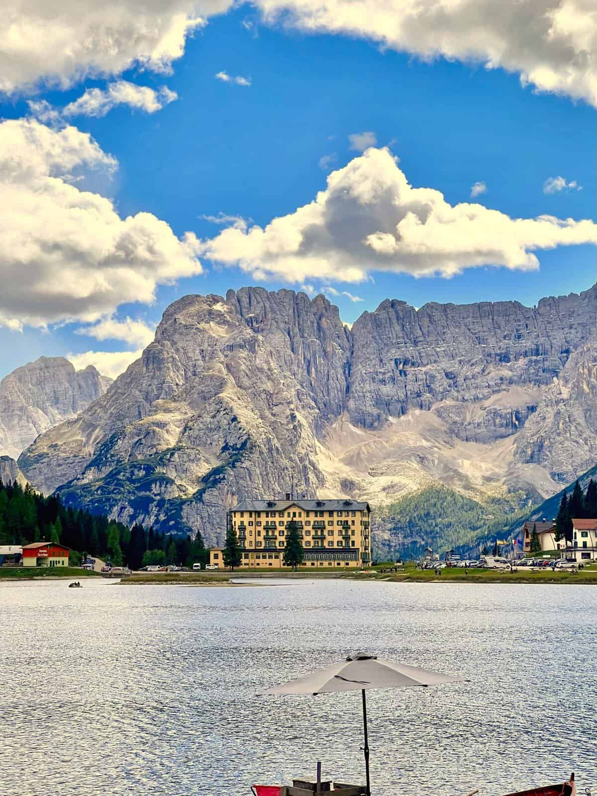 Hotel beside Lake Misurina with calm alpine water and the Dolomite mountains rising in the background.