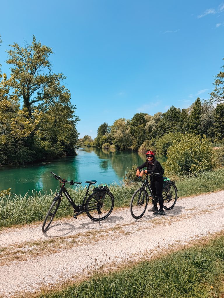 Two bikes and a woman next to a river close to Venice in Italy.